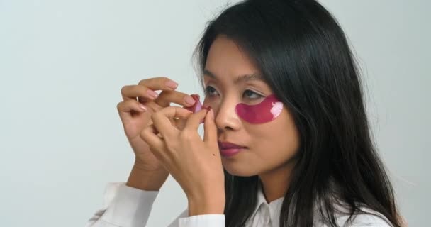 Portrét pozitivní korejské krásné mladé ženy etnické brunetky atraktivní dívka modelka na sobě fialové skvrny pod očima léčba pro péči o pleť rutiny doma během uzamčení, close-up ženské tváře — Stock video