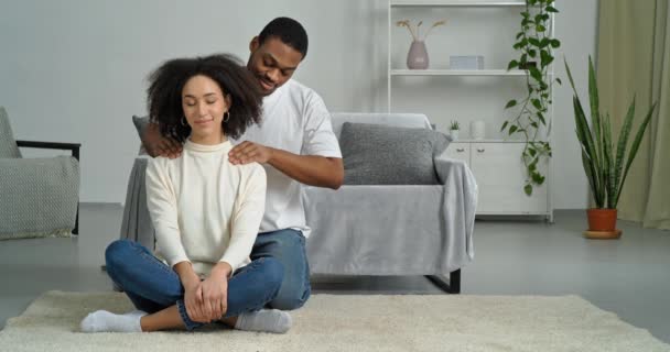Afroamerický pár doma tmavé pleti starostlivý muž manžel přítel masáže ramena své milované ženy přítelkyně manželka, kudrnaté vlasy dáma má jemný dotek chlapa cítí úlevu od stresu — Stock video