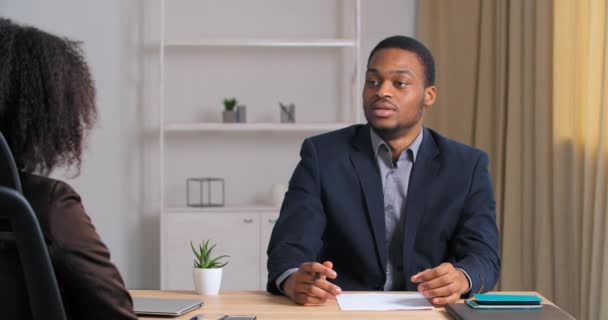 Focado jovem adulto afro-americano empresário apresentando ideia do projeto conversando no escritório para encaracolado parceiro irreconhecível feminino ou cliente fazendo oferta em negociações meetingbusiness mulher consultoria — Vídeo de Stock