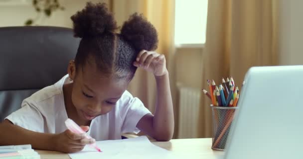 Porträt der süßen afroamerikanischen Mädchen sitzt zu Hause in der Schule im Kindergarten mit bunten Flamastern in den Händen zeichnet mit Bleistiften auf weißem Papier macht Bild entfernt in Laptop suchen — Stockvideo