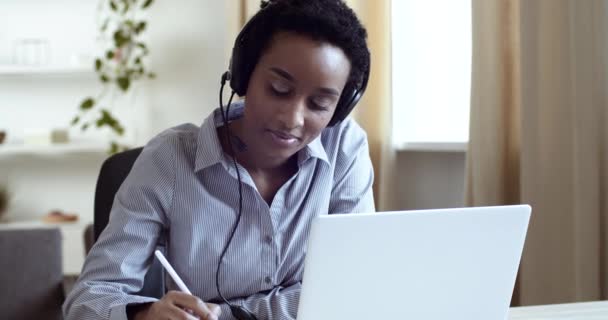 Biznes portret afro amerykański student mieszany rasa dziewczyna etniczna kobieta siedzi przy stole w domu biuro pracy na laptopie online pisanie notatek na papierze, e-learning pojęcie koronawirus epidemii kwarantanny — Wideo stockowe