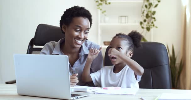 Genç anne Afro-Amerikan kadın öğretmen ve tatlı kızı liseli kız laptopun önünde oturmuş uzaktan ödev yapıyor ağ gülüşü yakından gülüyor. — Stok video