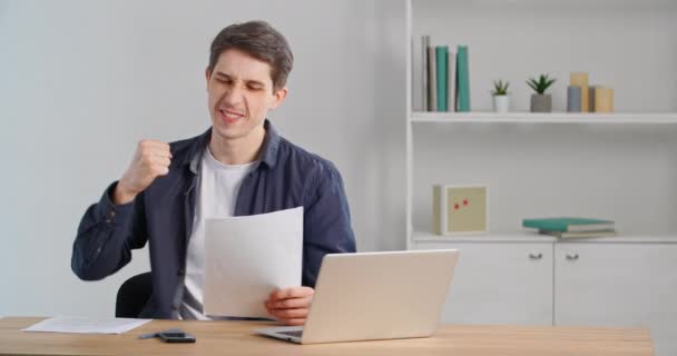 Homme caucasien en vêtements décontractés assis à la table lit lettre se réjouit gagne fait geste de la main de la victoire, gars reçoit une nouvelle offre d'emploi approbation pour les documents de position de la banque se sent ravi, concept de succès — Video