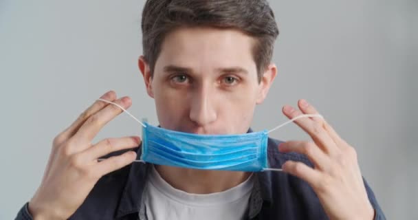 Portrait of responsible man looking at camera demonstrates how to properly wear medical face mask by closing his mouth and nose teaches safety rules and social norms during pandemic showing thumbs up — Stock Video