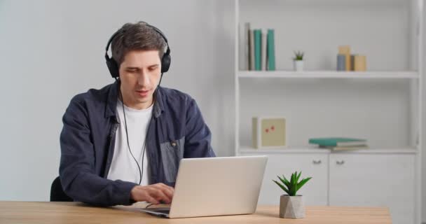 Blanke zakenman werkt met laptop online op afstand van huis typen surfen netto afwerking werk luisteren naar muziek met koptelefoon pauze genieten melodie sluiten zijn ogen van plezier — Stockvideo