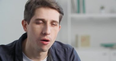 Yakın planda tatmin olmuş erkek yüzü, beyaz portre genç adam mutluluğu hissediyor tatlı, siyah bir tatlının tadını çıkarıyor ambalaj kağıdında çikolata yiyor içeride oturmaktan zevk alıyor.