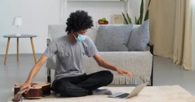 Afro-Amerikalı genç adam tıbbi koruyucu maske takmış gitar dersini bitiriyor. Laptop kapanıyor. Nilüfer pozisyonunda meditasyon yapıyor.