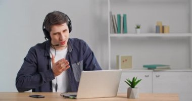 Masada oturan Kafkasyalı iş adamı, kulaklık takıyor, web kamerasına konuşuyor, uzaktan görüntülü konferans yapıyor, jestler yapıyor, öneriler üzerine düşüncelere yol açıyor, ev telgrafı çekiyor.