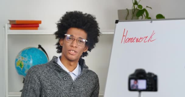 Professor afro-americano tutor masculino fica na lousa fala sobre lição de casa escrita registros vídeo lição ensina língua estrangeira para estudantes usando câmera moderna, aprendendo durante o bloqueio de quarentena — Vídeo de Stock