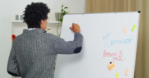 Portrait von afroamerikanischen Kerl Student junge Mathelehrer Tutor steht an der Tafel schreibt zeichnet Grafik erklärt Problem erzählt Lektion Blick auf Kamera nimmt die Brille ab, Konzept der Wissensvermittlung — Stockvideo