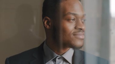 Pencereden, hayalperest Afro-Amerikan iş adamının yan yana baktığı, hayal kurduğu, fikir ürettiği, kameraya gülümseyen, onaylı bir şekilde başını sallayan projelere bakıyorum.