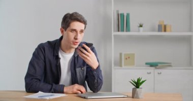 Genç, beyaz bir adam cep telefonuyla hoparlörden ses tanıma mesajı kaydediyor. Milenyum işadamı evdeki akıllı telefondan sanal uygulama servisiyle konuşuyor.