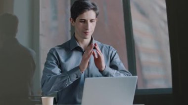 Kafkas iş adamı yöneticisinin portresi masada oturmuş dizüstü bilgisayara bakıyor avuç içlerine bakıyor dua ederken dua ediyor Çin geleneğindeki baş selamlamalarını ifade ediyor.