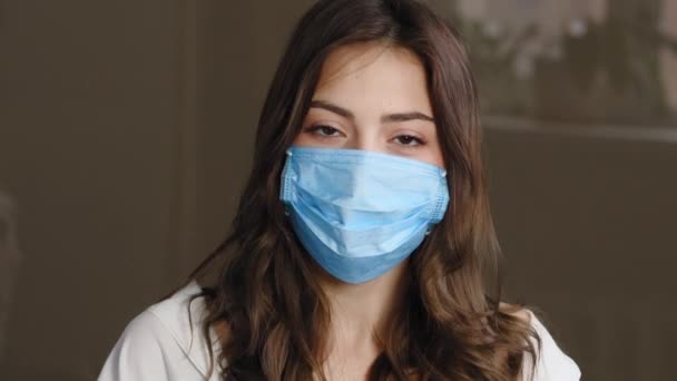 Portret pięknej brunetki cierpliwej dziewczyny zdejmuje ochronną maskę medyczną z kobiecej twarzy wyrzucając, uśmiechy szczerze raduje koniec pandemii, ciesząc się oddychaniem powietrzem, patrząc w kamerę — Wideo stockowe