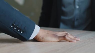 Üç kişiden oluşan çok uluslu bir grup el ele tutuşup masa başına avuç içlerini koyuyor, farklı etnik gruplardan iş adamları birleşiyor, takım çalışması yapıyor, destek oluyor.