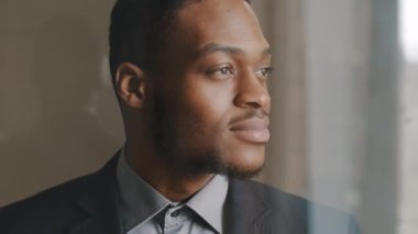 Afro-Amerikalı etnik iş adamı portresi. Profilde görünen, pencereden dışarı bakan, düşünceli, düşünceli bir karar veren, gelecek için derin planlar yapan, sorunları analiz eden girişimci yönetici.