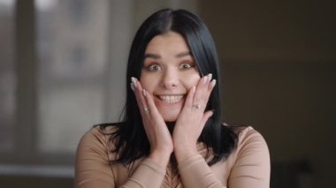 Portrait modest ethnic girl model plus size brunette millennial woman posing standing alone indoor, looking at camera with wide open eyes and mouth, feels surprise shock delight from unexpected news