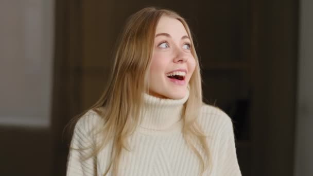 Portrait of happy enthusiastic young millennial woman opens her mouth in surprise looks around holding head with hands with joy. Close-up successful blonde girl wins feeling delighted with good news — Wideo stockowe