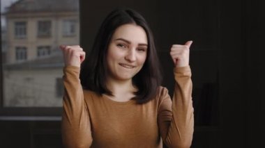 Neşeli esmer kız portresi kameraya bakıp parmağıyla onay jesti yapıyor. Kafkasyalı başarılı genç kadının yakın plan çekimi iyi ruh halinin sembolü.