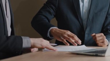 Tanımlanamayan Kafkasyalı işadamı ve Afro-Amerikalı yatırımcı anlaşma imzalarken ofis masasında el sıkışırlar. Erkek elini kağıt belgelerle kapat, el sıkış ve anlaşmayı imzala.