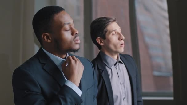 Two multiracial business men colleagues standing in office looking out window on break talking suffer from stuffy high temperature, afro american man with caucasian guy correcting collar from heat — Video Stock