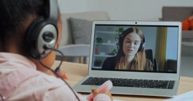 Karmaşık ırkın gerisinden bakıldığında, küçük liseli kız, karantina sırasında internet öğretmeni Kafkasyalı kadınla bilgisayar ekranında sohbet ederek evden uzaktan çalışmalar çekiyor.