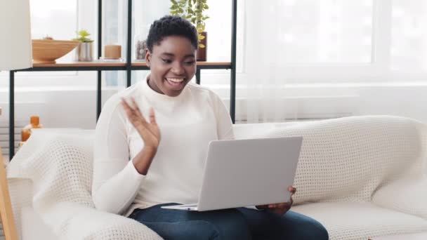 Young happy African American woman waving hand hello greeting talking at video calling conference chat looking at web cam. Afro ethnic black girl sitting at home couch sofa making online call remote — Stock Video