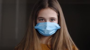 Kapalı alanda maskeli kadın portresi. Uzun saçlı liseli kız öğrenci kız öğrenci. Yüzüne koruyucu maske takıyor.