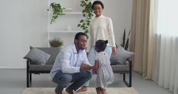 Tres afro negro mestizo personas jóvenes afroamericanos familia en casa, niña hija hija saltando hablando con papá hombre mientras mamá baila, niño asusta padre juega divertirse en sala de estar — Vídeos de Stock