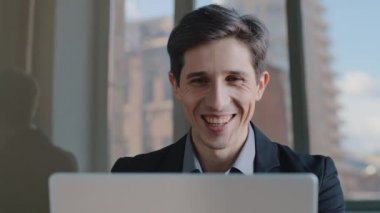 Kafkasyalı profesyonel iş adamı portresi dizüstü bilgisayarın ekranına bakıyor, çevrimiçi bilgisayar uygulamasını kullanıyor, ağda haberleri okuyor, gülüyor, çalışıyor, e-posta yoluyla teklif alıyor.