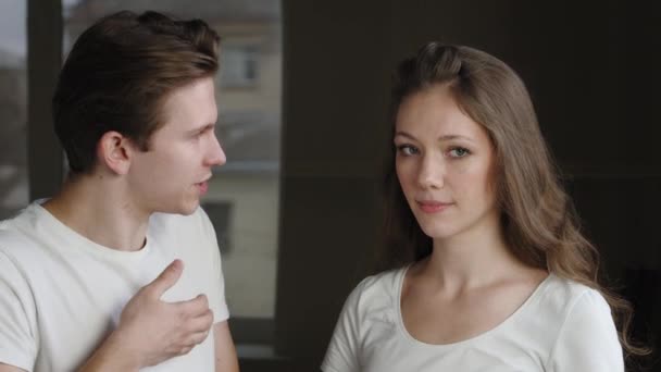 Portrait of caucasian couple friends girlfriend and boyfriend talking standing indoors. Close-up young family man guy emotionally speaks tells woman about problem, girl listens waves his head supports — Stock Video