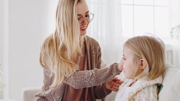 Young caring mother single mom adult woman care for child combing blonde hair of little girl daughter toddler uses comb hairbrush for morning beauty procedures at home preparing kid baby for school — Stock Video