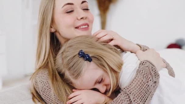 Young mother loving woman babysitter hugs little girl daughter child consoles comforts cuddles talks with beloved adorable baby smiling sitting at home, closeup female family portrait mum embraces kid — Stock Video