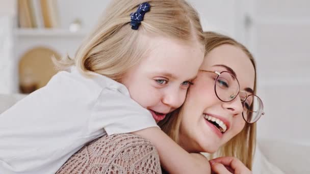 Familie huis portret kleine dochter blond schattig kind knuffels moeder jong vrouw met bril rond nek knuffels geliefde ouder, close-up gelukkig moeder lacht glimlachen praten met baby meisje ontspannen indoor — Stockvideo