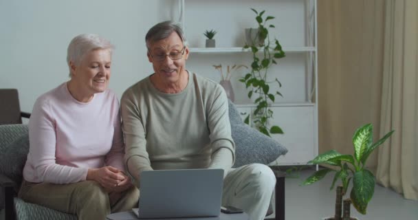 Gammal man och hustru mormor och morfar talar på videosamtal online konferens med modern teknik kommunicera med barn på distans bjuda in gäster gör välkommen gest med händerna — Stockvideo