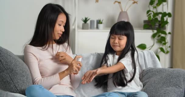Coronavirus Covid-19 quarantine concept. Asian mom treats daughters childs hands palms with disinfectant antiseptic spray sanitizer alcoholic gel against bacteria virus. Lockdown family lifestyle — Stock Video