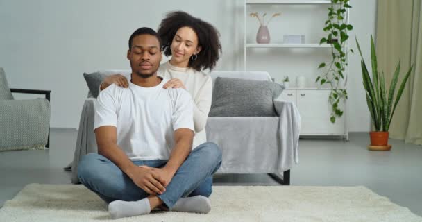 Afro amerykańska kobieta kochająca żona daje masaż dotykając ramion do zmęczonego męża uczucie bólu w szyi cierpi z powodu dyskomfortu niewygodna postawa dziewczyna dbanie o chłopaka w domu — Wideo stockowe