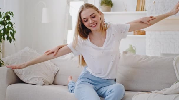 Feliz família em casa, amando a jovem mãe jogando jogo piggybacking bonito pequena filha engraçada sentar no sofá, alegre mamãe carregando pequena menina na parte de trás bonding fingindo voar interior — Vídeo de Stock