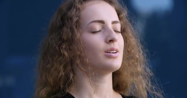 Lady model head shot standing street outdoors. Close-up female woman smiling face with closed eyes, enjoying breathes clean air deeply. Portrait curly-haired teenage girl with perfect skin. — Stock Video