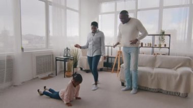 Afro-Amerikalı küçük kız Afrikalı anaokulu öğrencisi ebeveynlerin spor egzersizleri, etnik anne ve babaların kızını desteklemesi, melez babanın küçük çocuğu alkışlaması, çocuğa beş jest yapması,