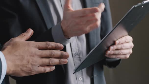 Close-up twee multiraciale zakenmannen afro-Amerikaanse en blanke collega 's die folder tablet met document rapport gebaren show met mannelijke vingers fout in kranten bespreken project onderhandelingen — Stockvideo