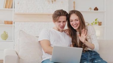 Birkaç genç beyaz aile, kadın ve erkek bilgisayarlı uygulama kullanarak evden video görüşmesi yapıyorlar. Bilgisayar kameralarına el sallıyorlar. Milenyum kızı ve adam uzaktan konferans sohbeti yapıyorlar.