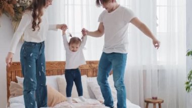Genç, sevecen, beyaz bir aile evde oyun oynuyor. Küçük kızıyla yatakta eğleniyorlar. Anne ve babası küçük kızı elleriyle havaya kaldırıyor.