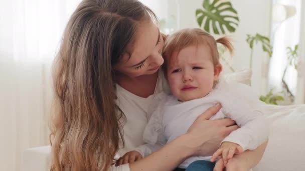 Jovem mãe caucasiana com choro criança triste doente menina bebê abraçando em casa, mãe carinhosa mãe solteira mulher acalma consoles cansado bebê bonito criança com lágrimas limpa nariz de criança com guardanapo de papel — Vídeo de Stock