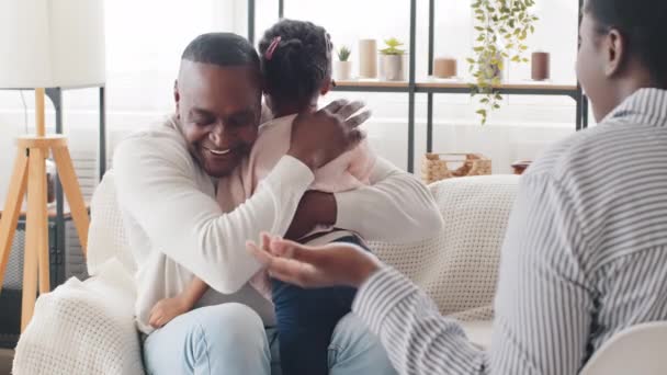 Volwassen man afrikaanse vader houden weinig dochter kind meisje praten met onherkenbaar onbekend afro vrouw zitten indoor, zwart zorgzame vader knuffelen knuffelen baby kind kalmeert verdrietig boos schoolmeisje consoles — Stockvideo