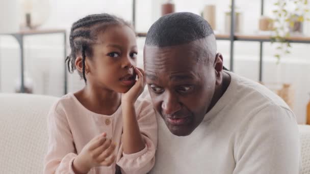 Niña negra afro-americana bebé nieta niño dice secreto al abuelo en oído compartir secreto información chisme, maduro años 50 hombre abuelo sorprendido escuchando niño, conversación familiar en casa — Vídeos de Stock