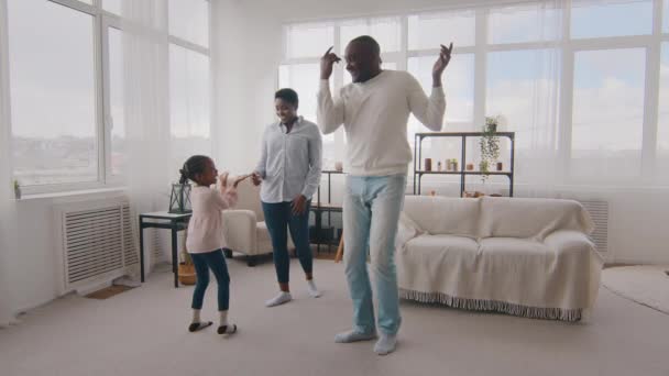 Afrikaans gelukkig familie dansen samen thuis in de woonkamer in het weekend vieren plezier hebben, actieve afro vader tonen dans spinnen kleine zwarte dochter kind kind knuffelen met etnische moeder vreugde — Stockvideo