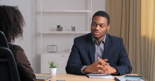 View from behind unrecognizable businesswoman curly lady boss listens to report idea of male colleague afro american businessman in formal stylish suit black speaks passes interview gets new job — Stock Video