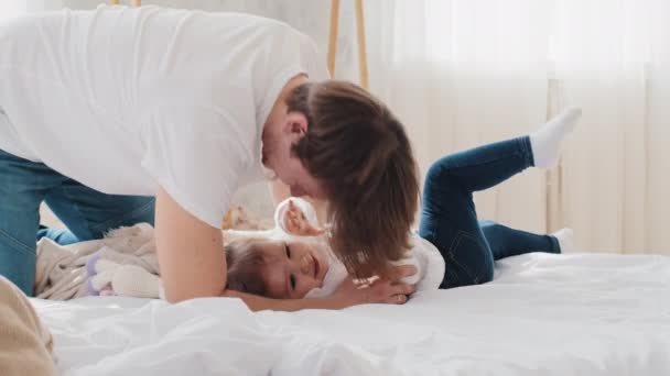 Houden van de jonge vader Kaukasische vader spelen spel met baby thuis liggend op bed, kietelen kind dochter klein meisje, lachen. alleenstaande ouder besteedt tijd met zuigeling peuter kind, familie binding en liefde — Stockvideo