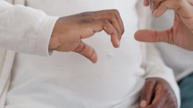 Genç bir aile babası hamile bir kadın ve sevgi dolu bir koca. Afrikalı bir adam parmaklarıyla kalp şekli yapar. Kapatın. Evli çift hamilelik karnının arka planında aşk işareti gösteriyor.
